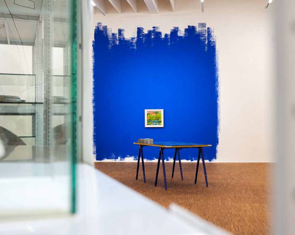 Ausstellungsansicht mit Tatiana Lecomtes Werk God Bless the Year 1942: eine Wand in kräftigem Blau mit einem einzelnen Landschaftsgemälde