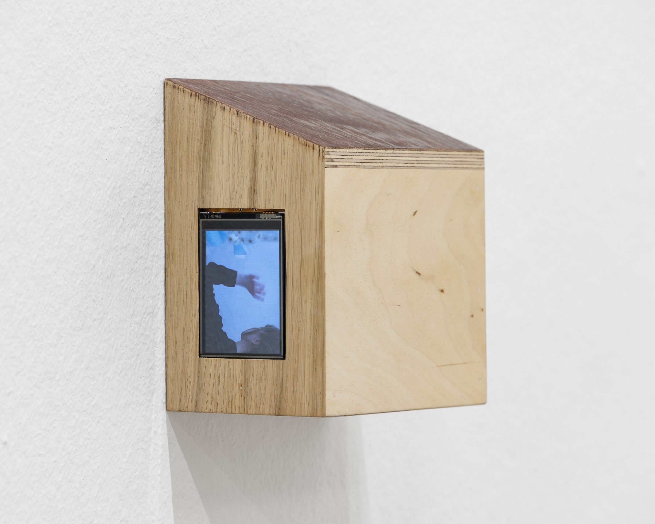Winziges Holzhäuschen mit eingelassenem Video einer winkenden Hand in Linda Lachs Ausstellung im Salzburger Kunstverein