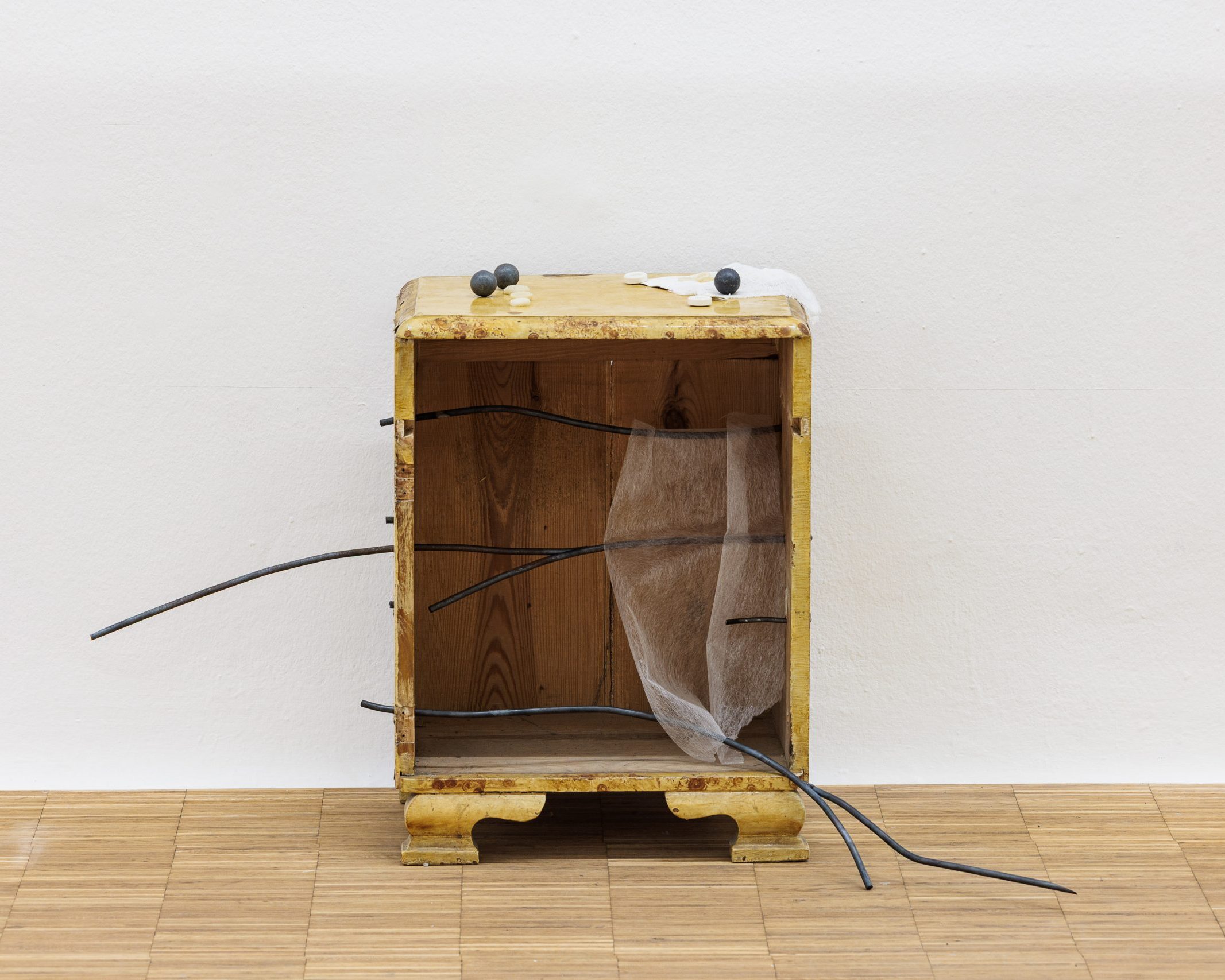 Verwittertes Holzkästchen mit Metallstäben und Stoff als Skulptur in Linda Lachs all keys all times im Salzburger Kunstverein