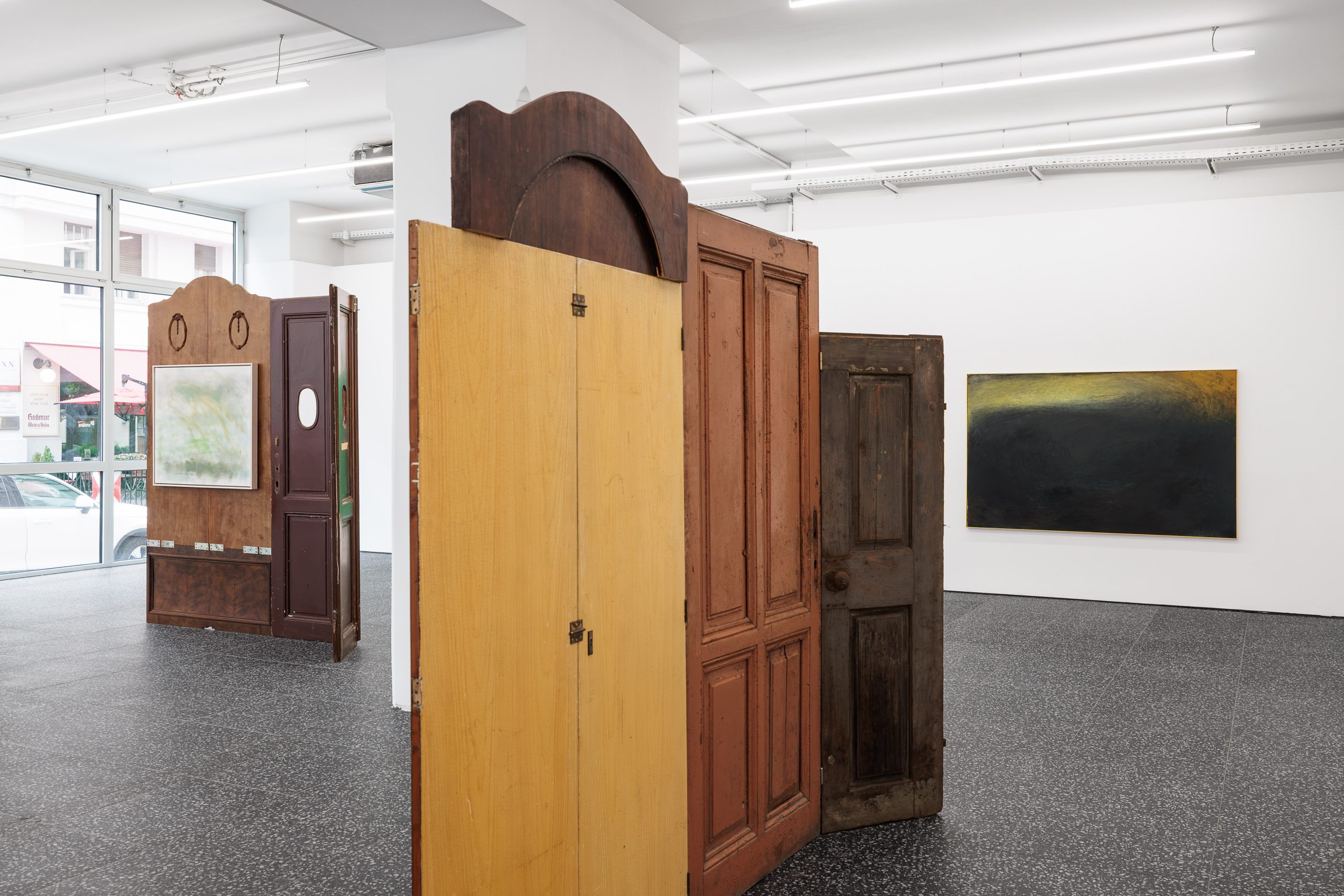 Lou von der Heyde inszeniert ein Theaterstück, in dem literarische Figuren und Kunstwerke inmitten eines bühnenbildartigen Settings aus Holztüren aufeinandertreffen.
