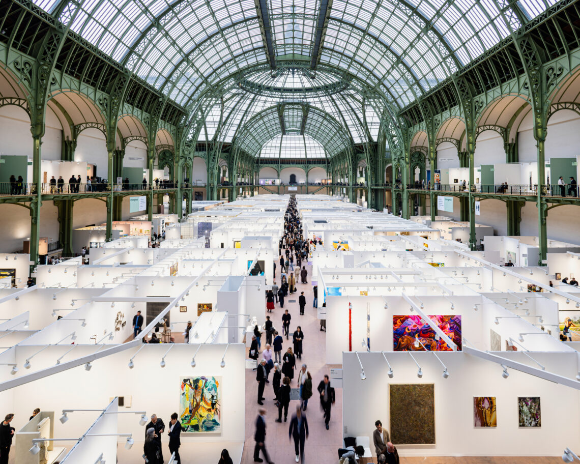 Blick von oben auf die Kunstmesse Art Basel Paris im Grand Palais: Messestände mit Gemälden unter der historischen Glas-Stahl-Kuppel, Besucher im Mittelgang